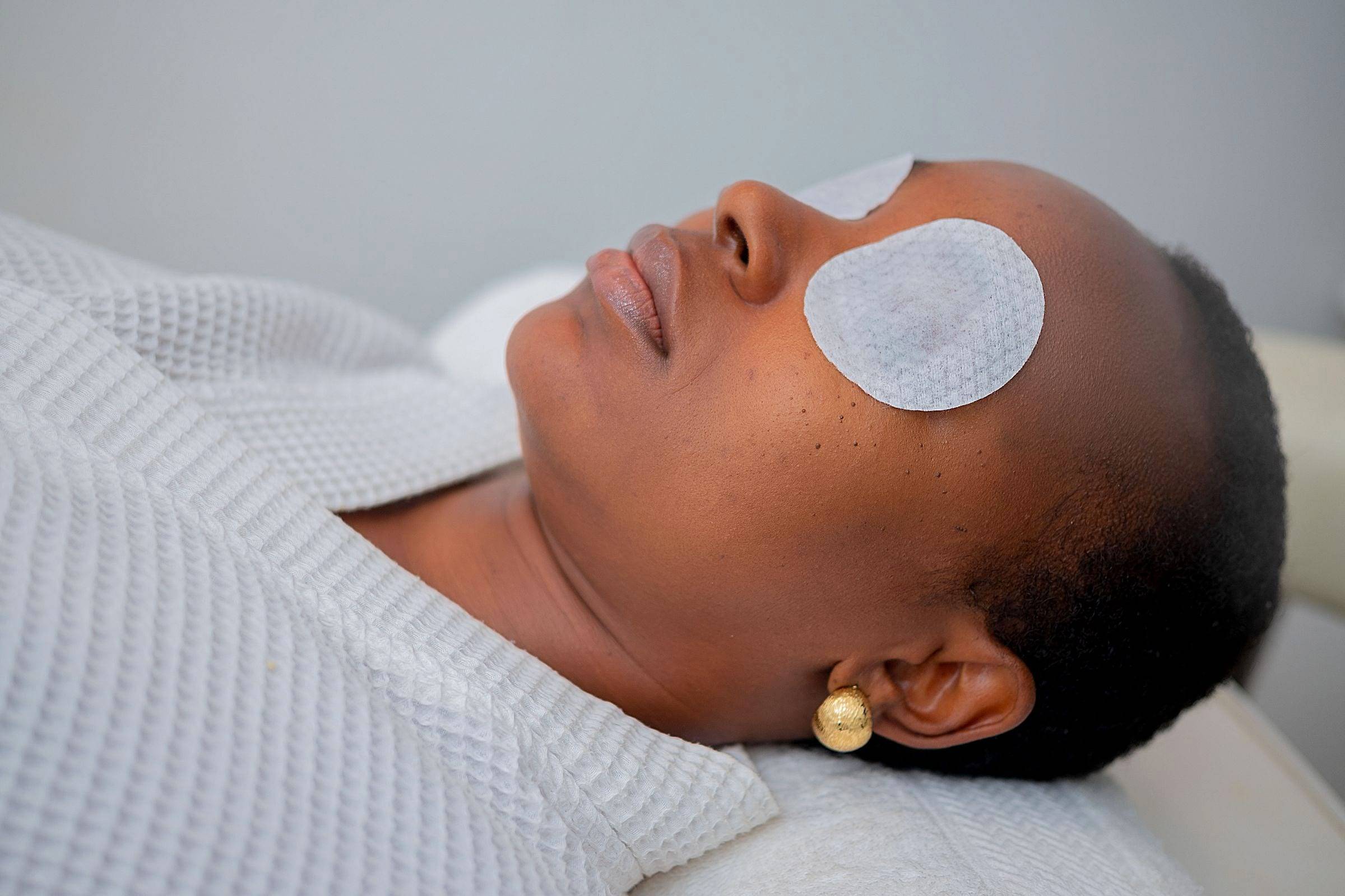 Mujer relajada con parches de algodón en los ojos durante un tratamiento facial