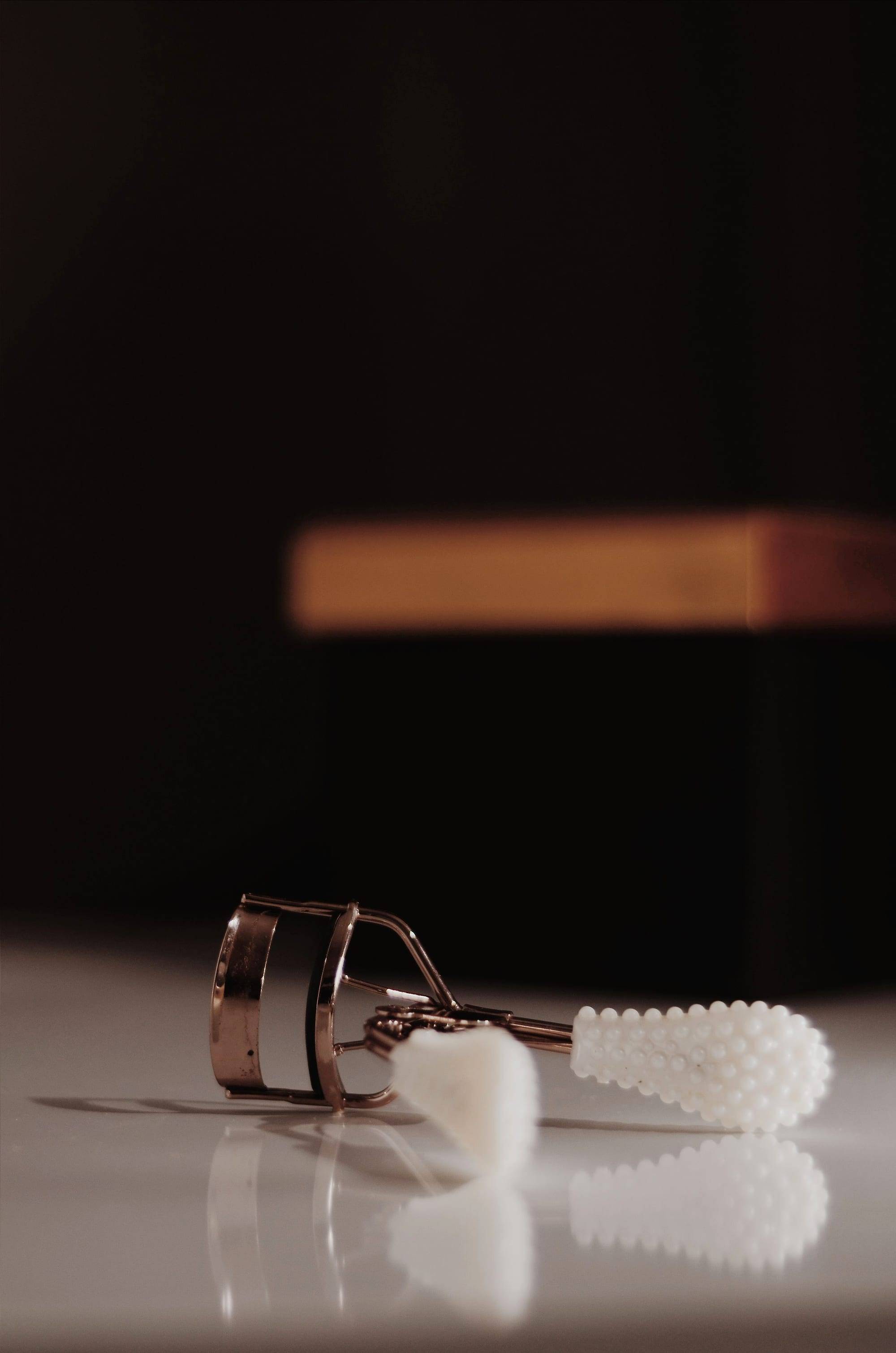 Rizador de pestañas sobre una superficie brillante con fondo oscuro